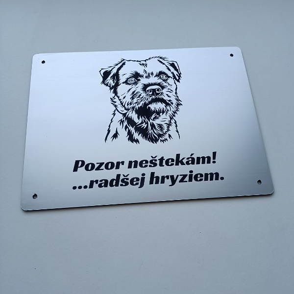 Strieborná tabuľka s border teriérom a nápisom Pozor, neštekám, radšej hryziem
